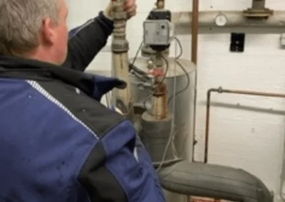 Monteur arbeitet an Absperrarmaturen und Rohrleitungen einer Heizungsanlage im Keller – TH Objekt Service & Dienstleistungen GmbH, Delmenhorst